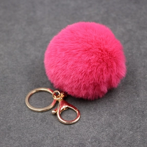 Détail d'un porte-clés pompon rouge rose avec anneau doré et fermoir mousqueton