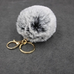 Close-up of fluffy black and white faux fur pompom with a golden alloy lobster clasp