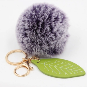 Detailed view of purple faux fur ball keychain with green leaf and gold metal clip