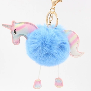 Detailed close-up of a blue faux fur unicorn pompom keychain with golden metal hardware