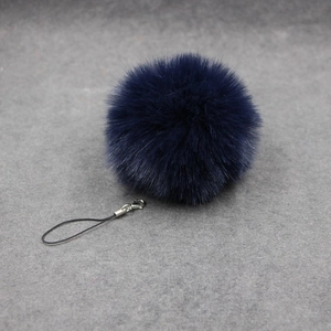 Macro detail of a navy blue fluffy faux fur ball keychain with silver lobster clasp hook
