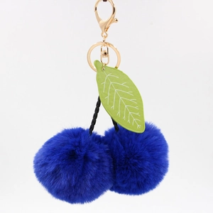 Détail du porte-clés cerise en fourrure bleu roi avec feuilles vertes et fermoir doré