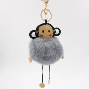 Detailed shot of grey faux fur monkey keychain with black leather head and gold clasp