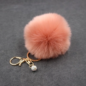 Close-up of pink faux fur pompom keychain with golden clasp and rhinestone ball charm