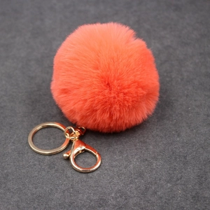 Détail d'un porte-clés pompon en fausse fourrure orange corail 8cm avec fermoir doré