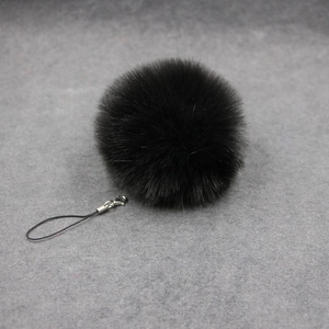 Detail of soft black faux fur pompom keychain with silver lobster clasp and strap