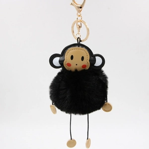 Close-up of fluffy black monkey plush keychain with golden metal clasp and faux fur ball
