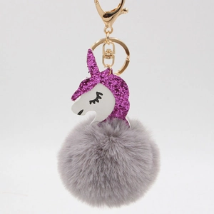 Detailed close-up of a unicorn keychain with purple glitter mane and fluffy grey pompom charm