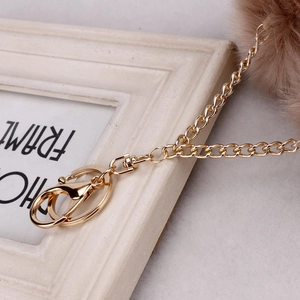 Detailed view of a golden lobster clasp with khaki faux fur pompom keychain