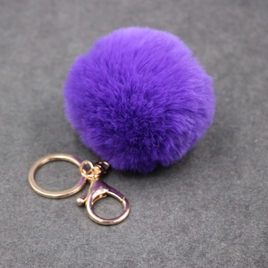 Détail du porte-clés pompon en fausse fourrure violet foncé avec fermoir doré