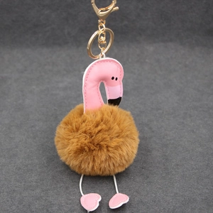 Détail d'un porte-clés flamant rose avec pompon marron et crochet en métal doré