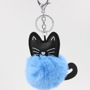 Detailed macro view of the fluffy blue faux fur pompom and black leather cat head pendant