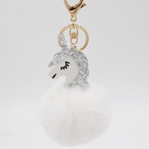 Detailed macro view of the fluffy white faux fur pompom and shiny silver sequin unicorn head