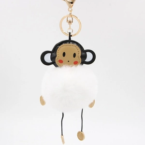Detail of cartoon monkey keychain with fluffy white faux fur pompom and golden metal clasp