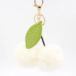 Détail du porte-clés cerise en pompon crème avec feuille verte et fermoir doré chic