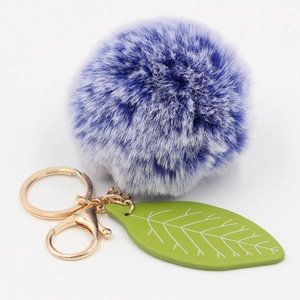 Detailed close-up of blue and white plush fur ball keychain with a green leaf and gold clasp