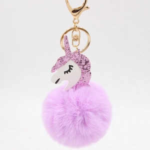 Detail of glittery pink unicorn head and purple faux fur ball on a gold keychain