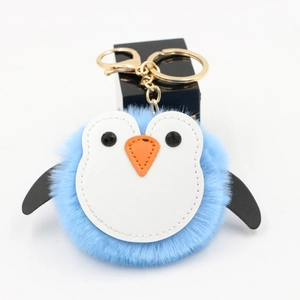 Détail du porte-clés pingouin en peluche bleue avec des attaches dorées