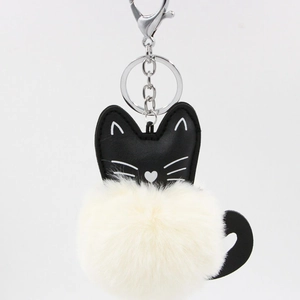 Detail of a black leather cat charm with a fluffy cream pompom and silver metal clasp