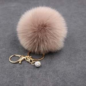Detail of light brown faux fur keychain with a golden lobster clasp and rhinestone ball