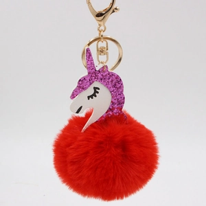 Close-up of fluffy red pom-pom unicorn keychain with purple glitter and gold metal clasp