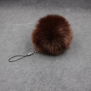 Detailed view of deep brown fluffy faux fur pompom with a black string and metal clasp