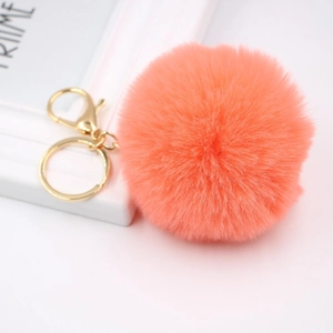 Detailed view of fluffy coral pompom keychain with golden lobster clasp for handbags