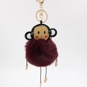 Detail showing plush monkey keychain with burgundy faux fur and golden lobster clasp