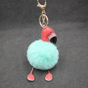 Détail du porte-clés flamant rose avec pompon vert menthe et attaches dorées en métal