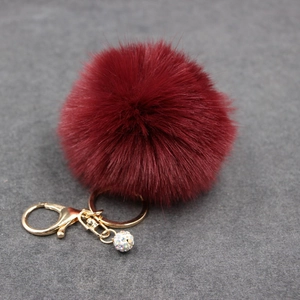 Macro detail of wine red faux fur keychain with gold lobster clasp and crystal ball