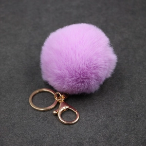 Détail d'un porte-clés pompon en fausse fourrure violette avec fermoir mousqueton doré