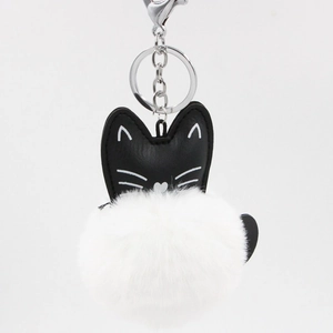 Detail of cute cat plush keychain featuring black PU leather and a soft white fur ball