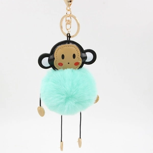 Detail of mint green plush monkey keychain with leather head and gold metal hardware