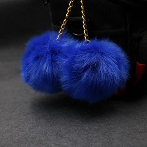 Detail of royal blue faux rabbit fur double pompom keychain with golden metal chain