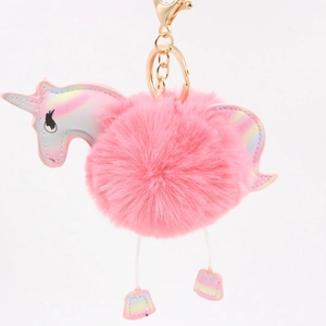 Detailed close-up of pink fluffy unicorn keychain with iridescent wings and golden clip