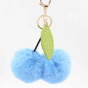 Détail du charm de sac cerise en fausse fourrure bleu clair avec feuille et crochet doré