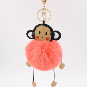 Detailed close-up of a pink faux fur monkey keychain with golden lobster clasp and charms