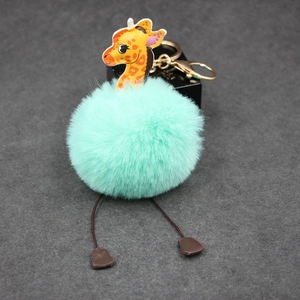 Detail of mint green plush puff keychain with cartoon giraffe and gold metal clasp