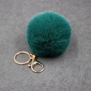 Gros plan détaillé d'un pompon en fausse fourrure vert foncé avec mousqueton doré chic