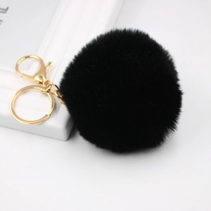 Detailed view of a soft black faux fur pompom keychain with elegant golden hardware links