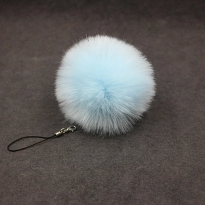 Detailed view of light blue faux fur pompom keychain with silver clasp and black cord