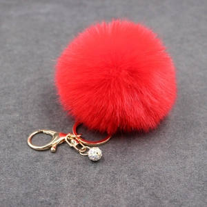 Detail view of 8cm vibrant red faux fur pompom keychain with golden clasp and crystal ball