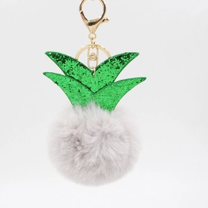 Detail of pineapple plush keychain featuring gray faux fur and green glitter leaves