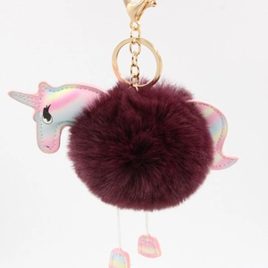 Detail of burgundy faux fur unicorn pompom keychain with iridescent wings and golden clasp