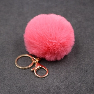Détail d'un pompon en fausse fourrure rose vif avec fermoir et anneau en métal doré