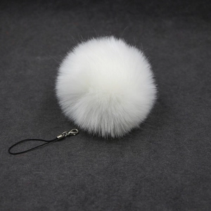 Detail of white faux fur pompom keychain with soft texture and metallic lobster clasp