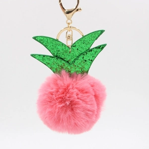 Macro view of pink pineapple faux fur keychain with green sequins and gold metal clasp