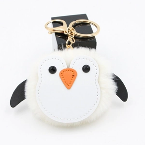 Détail d'un porte-clés pingouin en peluche blanche avec anneau doré et mousqueton