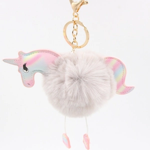Detail of colorful unicorn pompom keychain with golden metal clasp and soft plush texture
