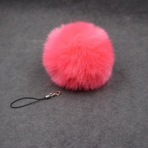 Detail of neon pink faux rabbit fur pompom charm with silver lobster clasp and black lanyard